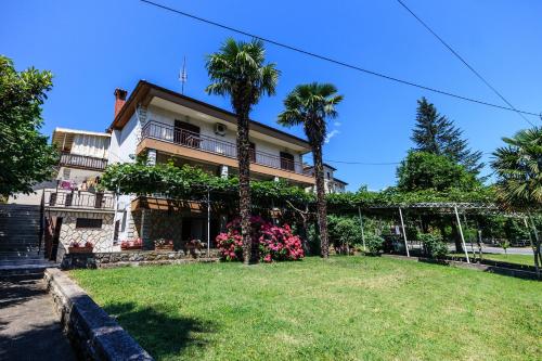 a house with palm trees and a yard at Rooms Sanja, Lovran - Opatija in Lovran
