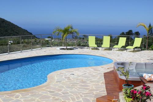 a swimming pool with chairs and a table and the ocean at Les Nymphes De Bourbon in Saint-Pierre