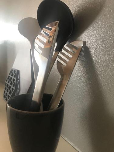 three utensils are in a black holder next to a wall at Timehouse Serviced Apartments in Munich