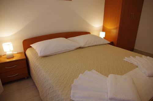 a bedroom with a bed with two pillows and two lamps at Apartments Sonja Podgora in Podgora
