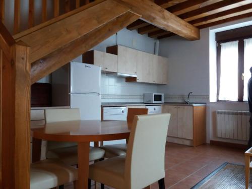 a kitchen with a wooden table and white cabinets at Casa Rural La Antigua Fragua in Los Llanos de Tormes