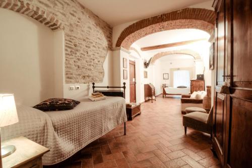 um quarto com uma cama e uma cadeira num quarto em Il Vecchio Comune em Santa Sofia