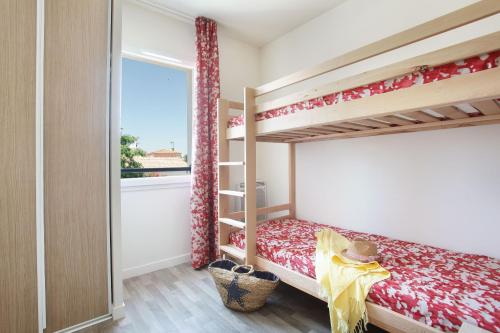 a bedroom with two bunk beds and a window at Résidence Odalys Fleur de Sel in Aigues-Mortes