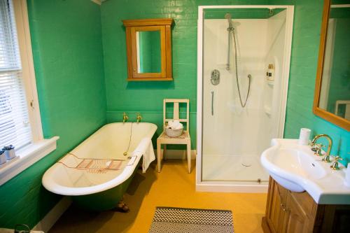 a green bathroom with a tub and a sink at Coldstream Estate - The Whare in Coldstream