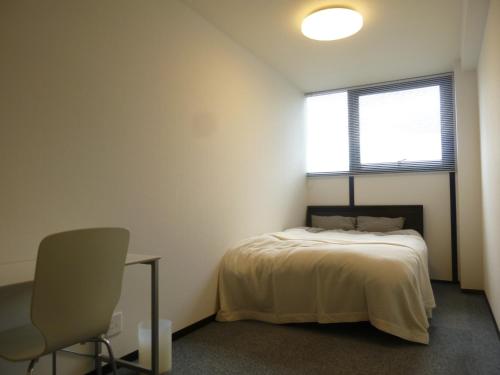 a bedroom with a bed and a chair and a window at Nagoya Motoyama House D in Nagoya