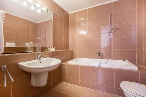 ein Badezimmer mit einem Waschbecken, einer Badewanne und einem WC in der Unterkunft Amadria Park Beach Hotel Niko in Šibenik