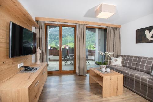 a living room with a couch and a tv at Alpenherz Ferienwohnungen in Pertisau