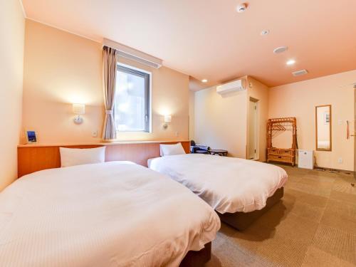 a bedroom with two beds and a window at Hotel Belleforet in Tsushima