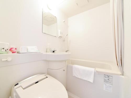a white bathroom with a toilet and a sink at Hotel Belleforet in Tsushima