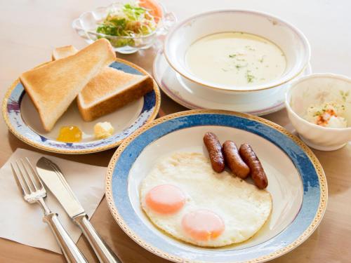 a table topped with plates of food with eggs and toast at Hotel Belleforet in Tsushima