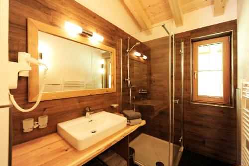 a bathroom with a sink and a mirror and a shower at Chalet Fuhrmannslochhof in Nauders