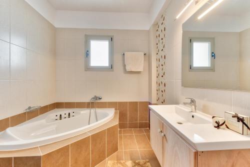 a bathroom with two sinks and a tub and a mirror at Villa Penelope in Kalpaki