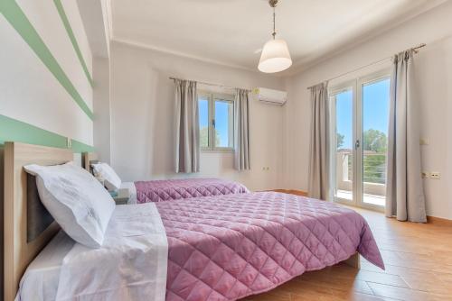 a bedroom with a large pink bed and windows at Villa Penelope in Kalpaki