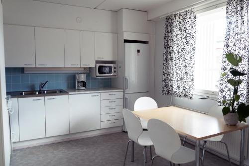 a kitchen with white cabinets and a table and chairs at Summer Apartments Mänttä in Mänttä