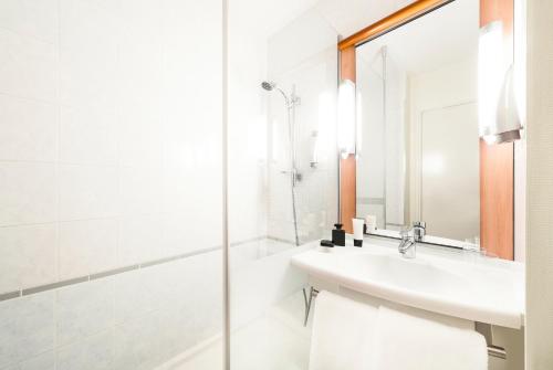 een witte badkamer met een wastafel en een douche bij ibis Châtellerault in Châtellerault