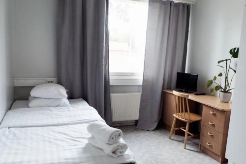 a bedroom with a bed and a desk and a window at Summer Apartments Mänttä in Mänttä