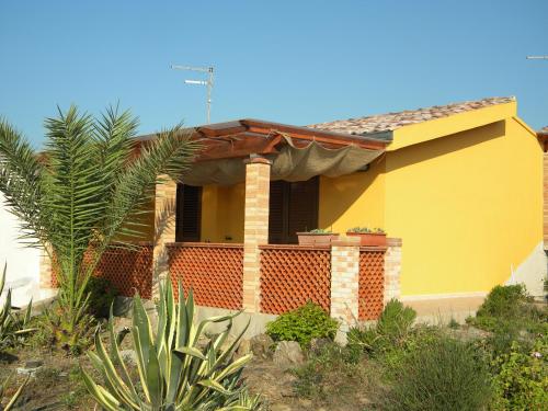 a yellow house with a palm tree in front of it at Villetta Albachiara in Sant' Antonio di Santadi