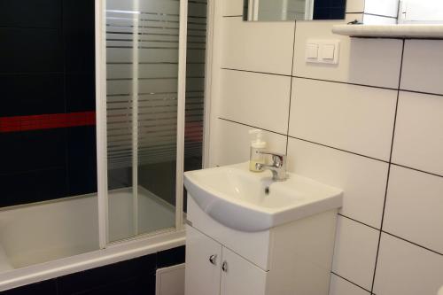 a white bathroom with a sink and a shower at Pokoje Gościnne in Lębork