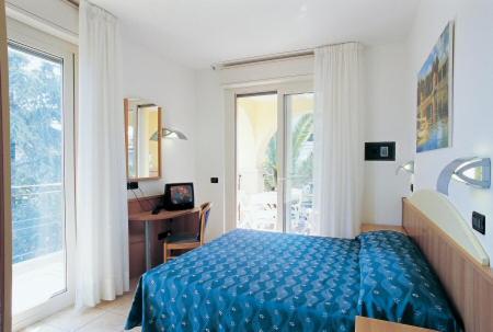 a bedroom with a bed and a desk and a window at Residence Le Palme in Alba Adriatica