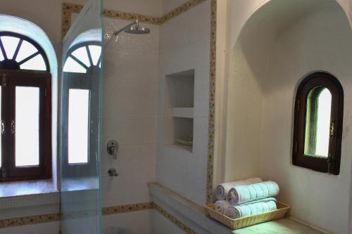 a bathroom with a tub and a shower with a mirror at Barabagh Deogarh - A Heritage Farm Stay in Devgarh