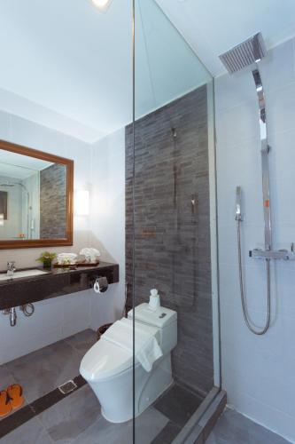 a bathroom with a toilet and a glass shower at Eskala Hotels and Resorts in Ngwesaung