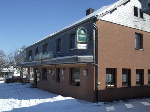 a building with a sign on it in the snow at Pension Brunnenhof in Roetgen