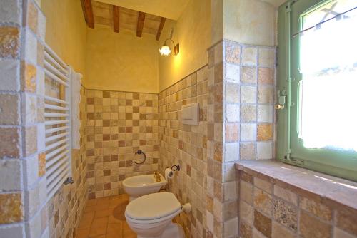 a bathroom with a toilet and a window at Castelmuzio by PosarelliVillas in Castelmuzio