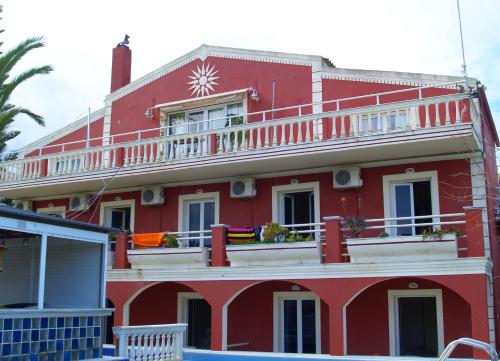 a red house with a balcony on top of it at Crystal in Kavos