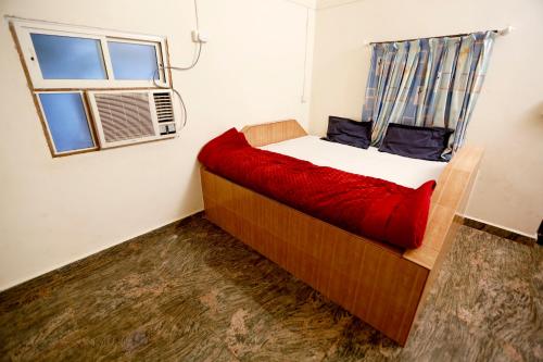 1 dormitorio con 1 cama con manta roja y ventana en Ashoka Villa 3 BHK Mahabaleshwar, en Mahabaleshwar