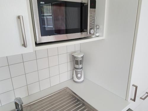 a microwave on a shelf above a kitchen sink at Apartment Voorhorst in Wagrain