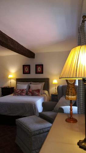 a bedroom with a bed and a couch and a lamp at La Casita del Tejo in Hervás