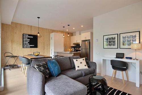 a living room with a couch and a kitchen at The Modern Cocoon in Quebec City