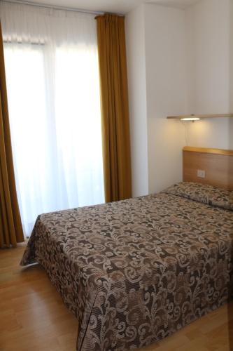 a bedroom with a bed with a brown blanket at Hotel Bellevue in Lignano Sabbiadoro