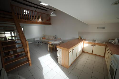 eine Küche mit einer Treppe und einem Tisch in einem Zimmer in der Unterkunft Le Bois Tableau in Muron