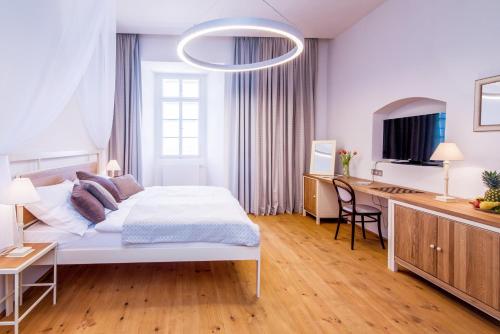 a white bedroom with a bed and a desk at Hotel Zámek Svijany in Svijany