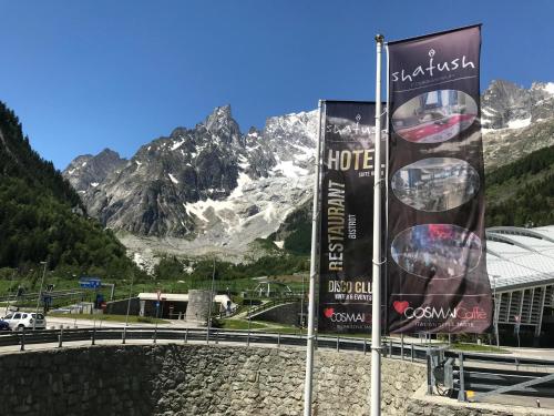 two billboard signs in front of a mountain at Shatush Hotel in Courmayeur