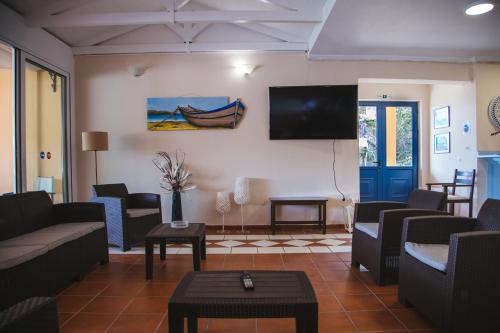 a living room with couches and a flat screen tv at Ionio Hotel in Nikiana