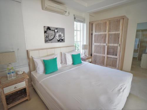 a bedroom with a large white bed with green pillows at Mayo Resort in Umeanyar