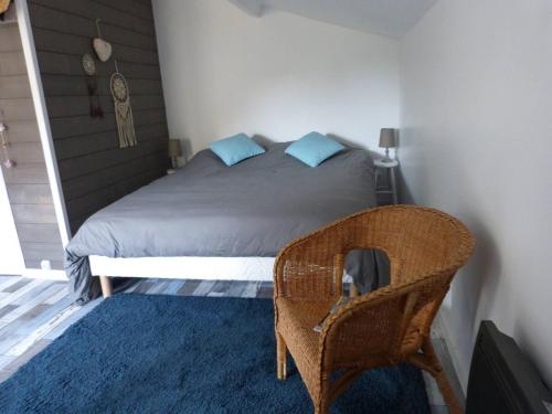 - une chambre avec un lit et une chaise en osier dans l'établissement APPART D'HOTES BRIVE OUEST (USSAC), à Ussac
