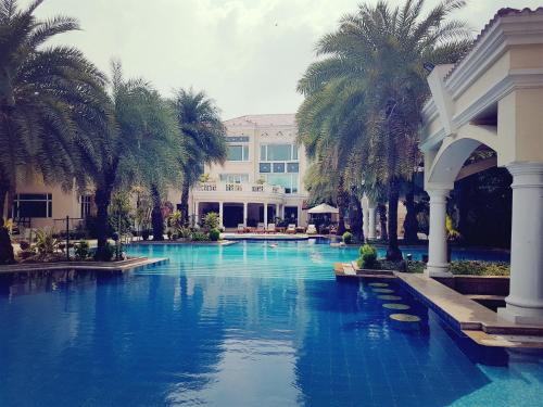 una piscina con palmeras frente a un edificio en The Palms Town & Country Club - Resort en Gurgaon