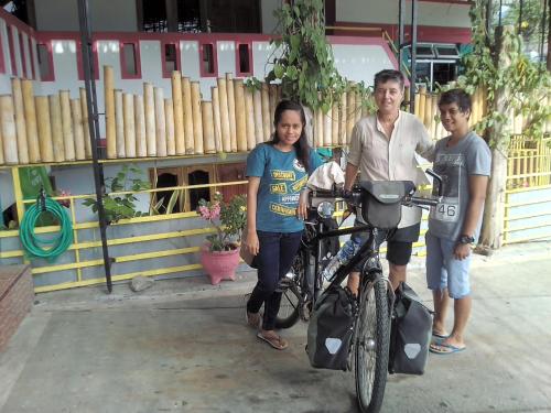 a man and two children standing next to a bike at Dasi Guesthouse in Ende