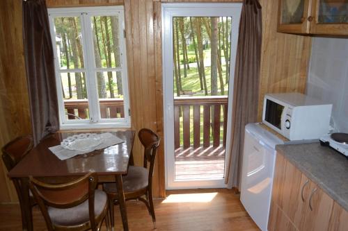 a kitchen with a table with a microwave and a balcony at Kotedžas prie pušelių in Nida