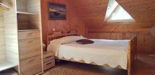 a bedroom with a bed in a wooden cabin at Kotedžas prie pušelių in Nida