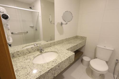 W łazience znajduje się umywalka, toaleta i lustro. w obiekcie Promenade Soho Campos dos Goytacazes w mieście Campos dos Goytacazes
