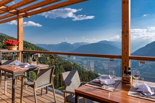 a table and chairs on a balcony with a view of mountains at Mountain Lodge Prennanger in Schenna