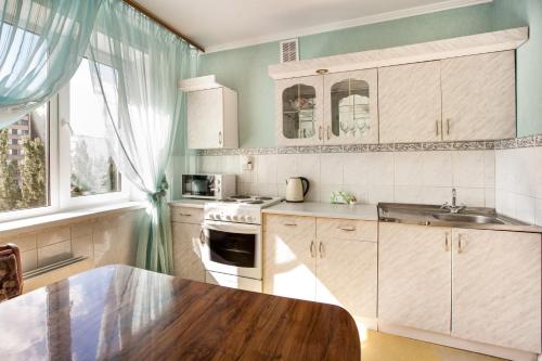 トリヤッチにあるКвартира на Бульваре Гаяの白いキャビネットと木製テーブル付きのキッチン
