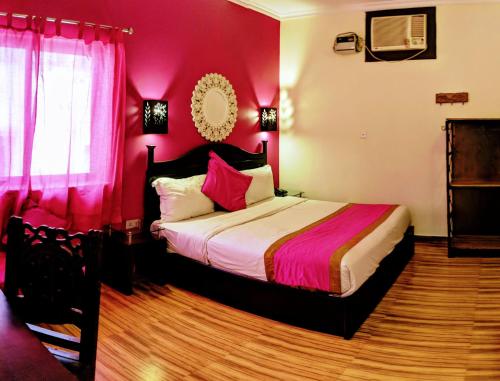 a bedroom with a large bed with pink walls at La Casa in Haridwār