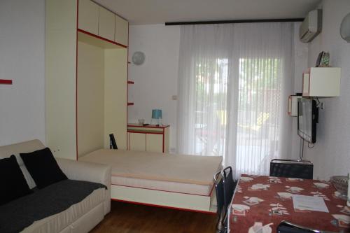 a bedroom with a bed and a couch and a window at Apartmajsko naselje Žusterna in Koper