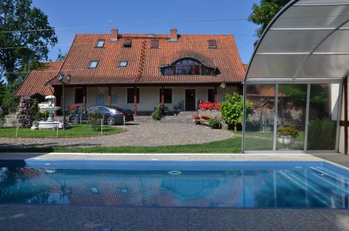 a house with a swimming pool in front of a house at Dworek Mazurski Lizer in Stręgielek