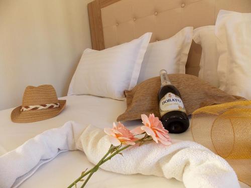 a bottle of wine and a hat on a bed at Studios Kentia in Skala Marion